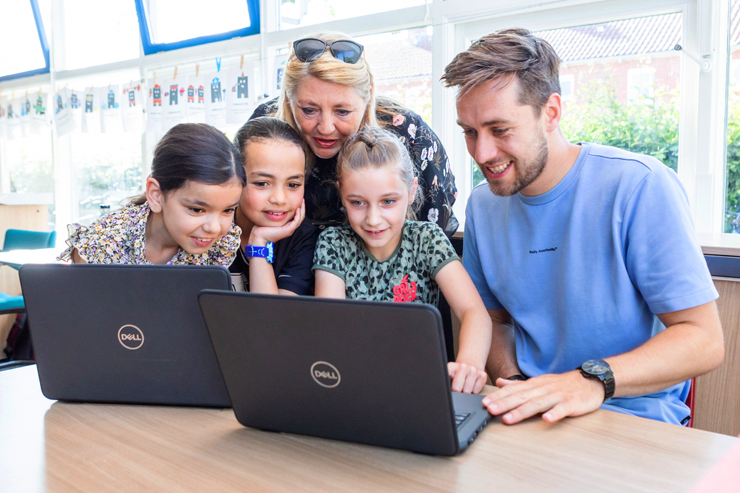 Leerlingen en leerkrachten Oosterhoogebrugschool achter laptop.